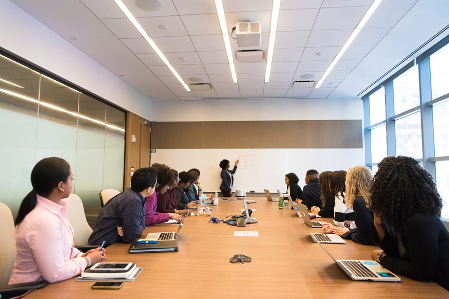 Corporations_Non-Profits Woman presents on a whiteboard at a meeting.