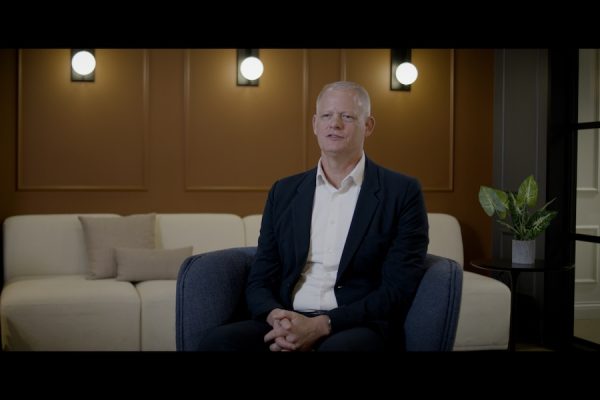 Phil Andrew, founder of PAX Group, sitting during a video interview