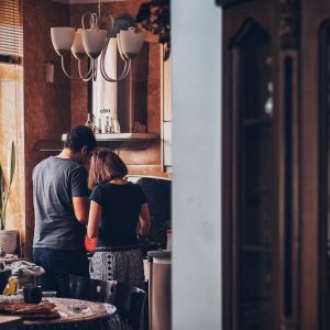 Man and woman standing over a stove in a kitchen