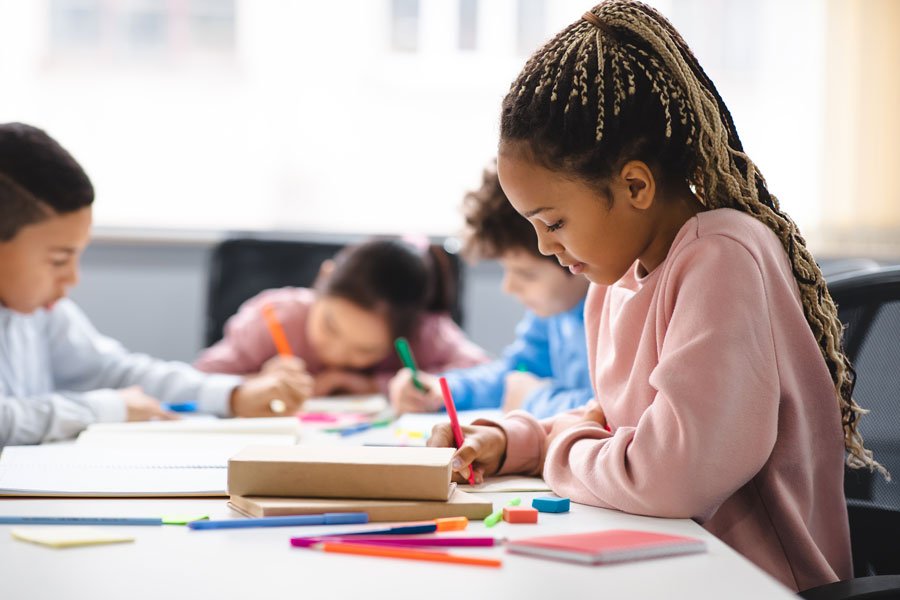 young-girl-classroom Children around a table coloring